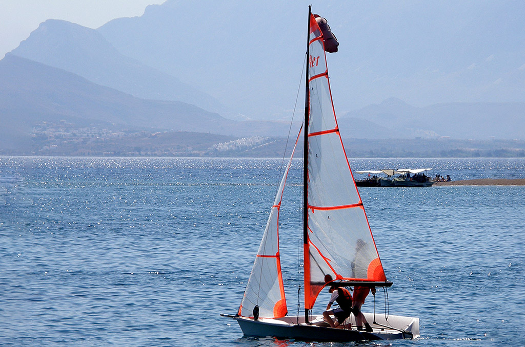 Barca a vela 29er in navigazioni condotta da due giovani con delle barche sullo sfondo