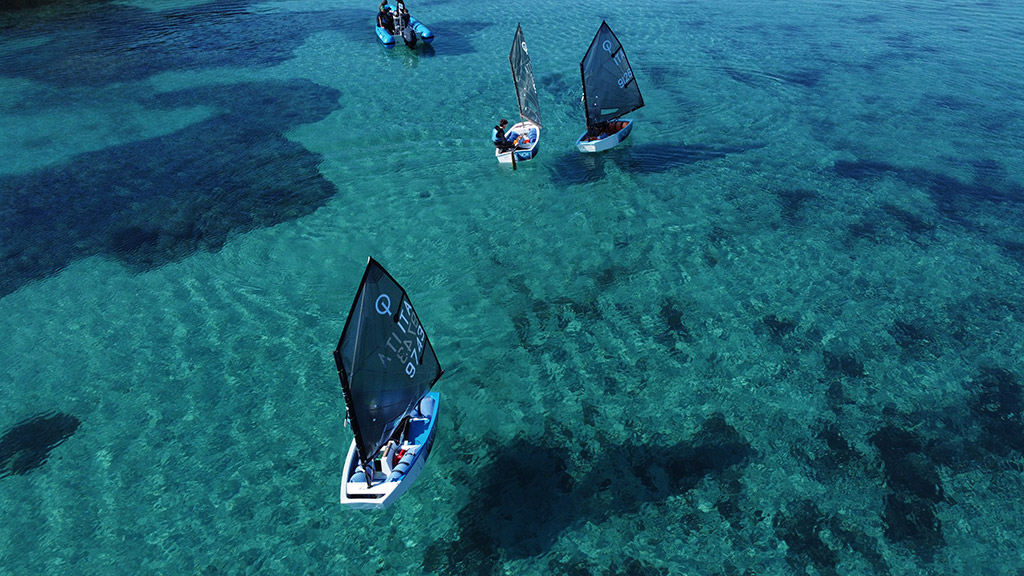 Veduta dall'altro di Optimist ecosostenibili della Nox Oceani. Mare cristallino e giovani che si divertono.